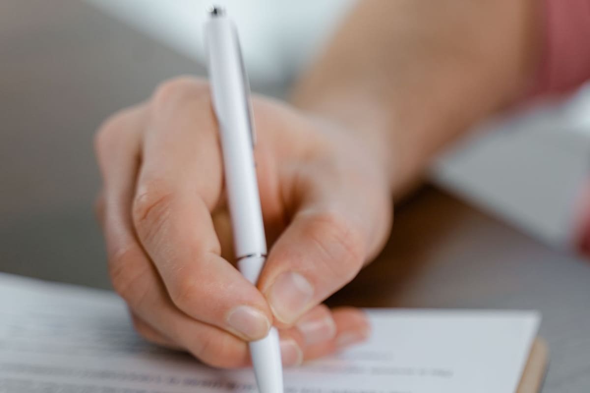 Mão assinando um documento com caneta