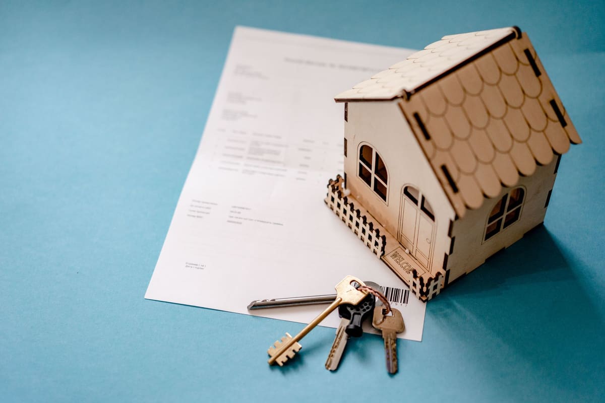 Miniatura de casa ao lado de um contrato e de um molho de chaves